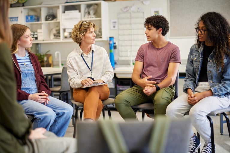 Multiethnic teenagers sitting in a circle engaged in group conversation for psychological support
