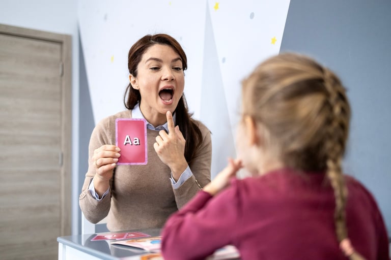 Speech therapist working with a young girl, teaching letter A phonetics and articulation