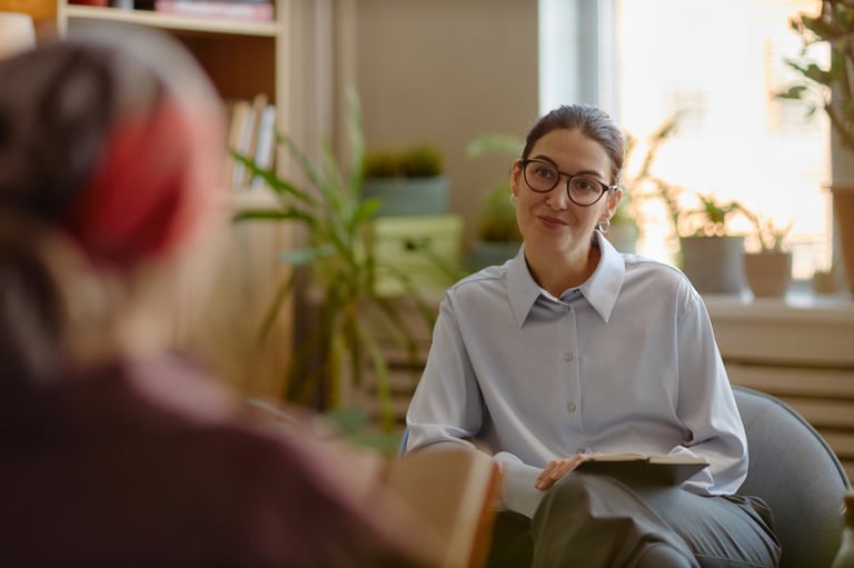 Caucasian young adult woman psychologist wearing glasses listening attentively to unseen patient during therapy session