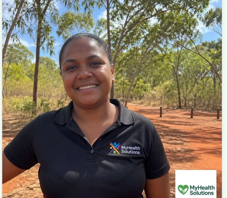 Woman in MyHealth Solutions uniform smiling outdoors in a forest clearing on red soil
