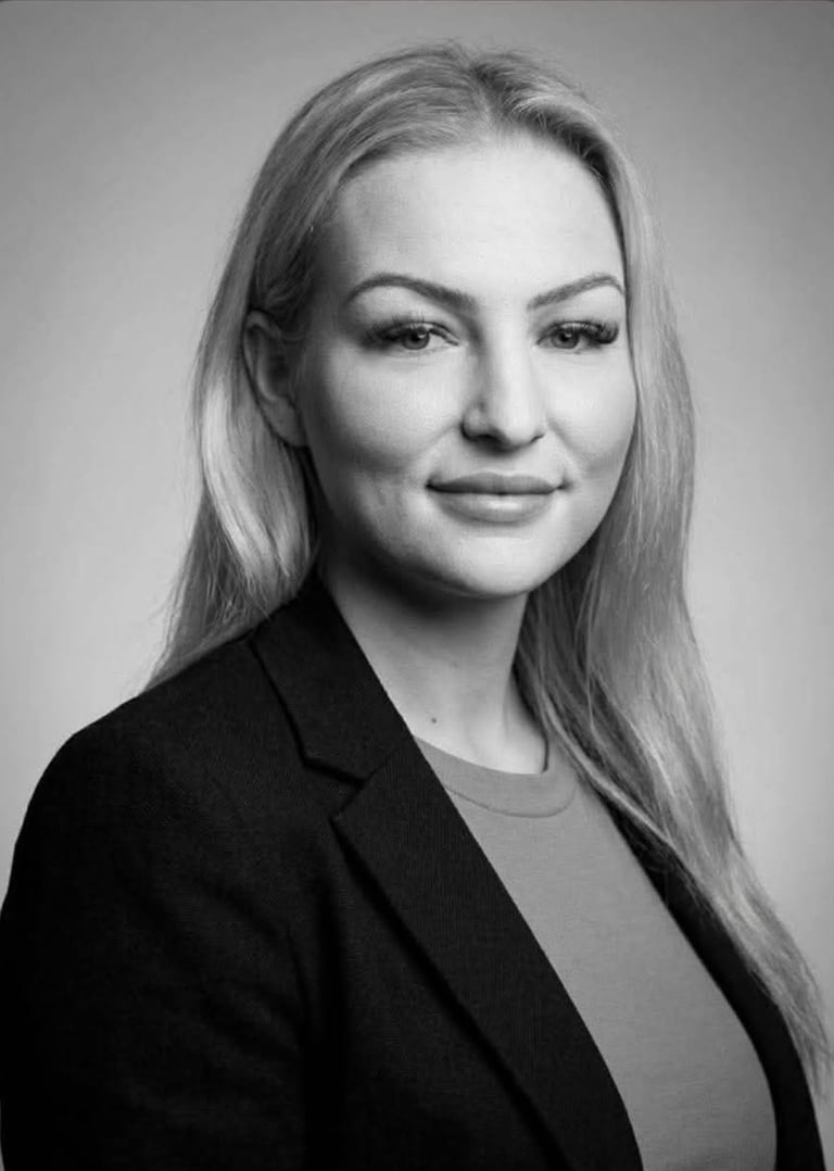 Black and white portrait photograph of a woman with long straight hair wearing a dark blazer over a light top