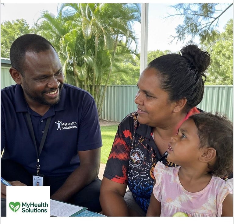 Healthcare worker in MyHealth Solutions uniform smiling with a mother and young child during a consultation in a bright, plant-filled office